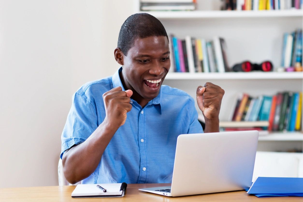 a man excited in front of his laptop